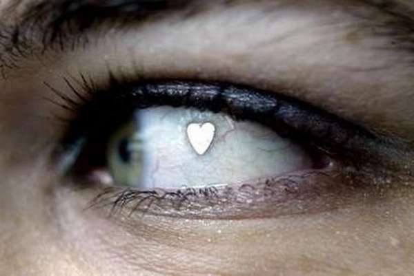 Vemos un ojo de color claro que tiene  un corazon alli pegado en la parte blanca del ojo