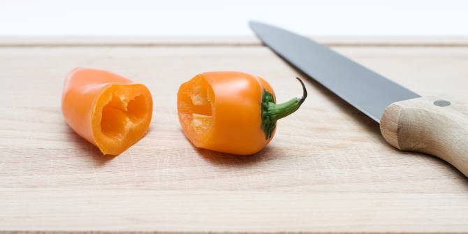 Un pimiento partido a la mitad por un cuchillo sobre una tabla