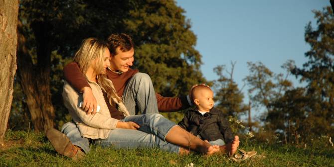 Una pareja con su hijo pequeño viendo el atardecer en el bosque