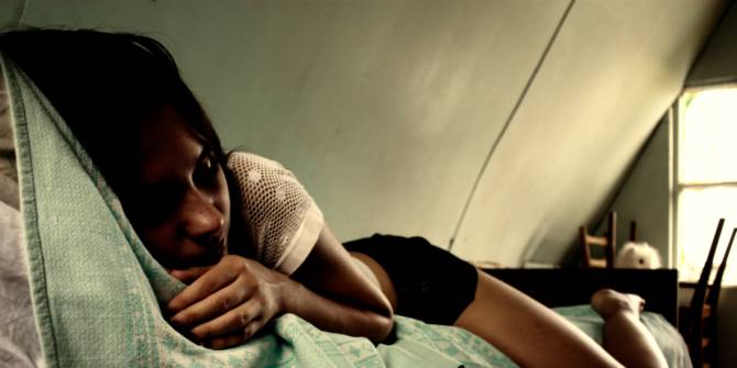 Una joven deprimida está acostada sobre su cama en una habitación