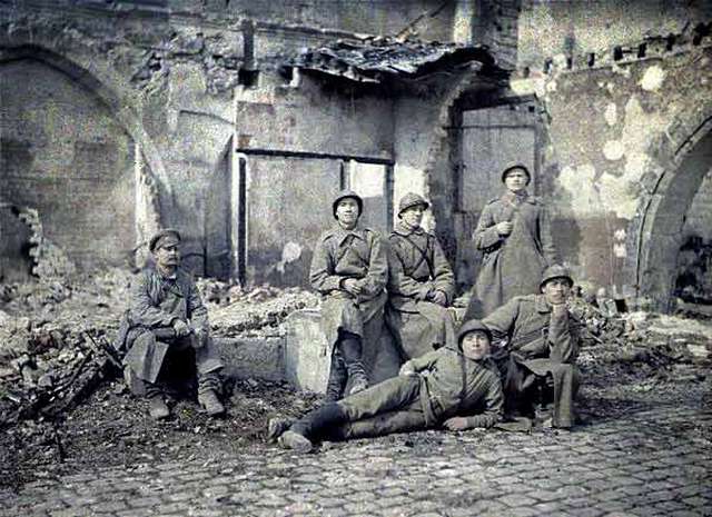 Un grupo de soldados con uniformes y abrigos comparten en las ruinas de un sitio