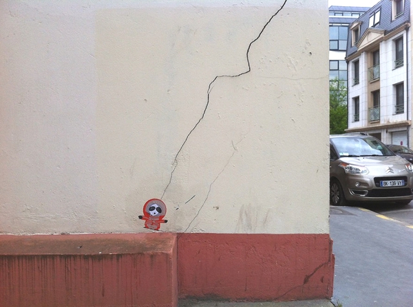  Vemos una pared blanca con un zócalo rojo y una grieta que recorre toda la pared al final hay una muñeca que parece atada a una cuerda y es la grieta que hace las veces de cuerda 