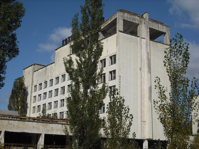 Vemos un edificio con muchas ventanas y algo alto tiene vegetación por los lados de la construcion