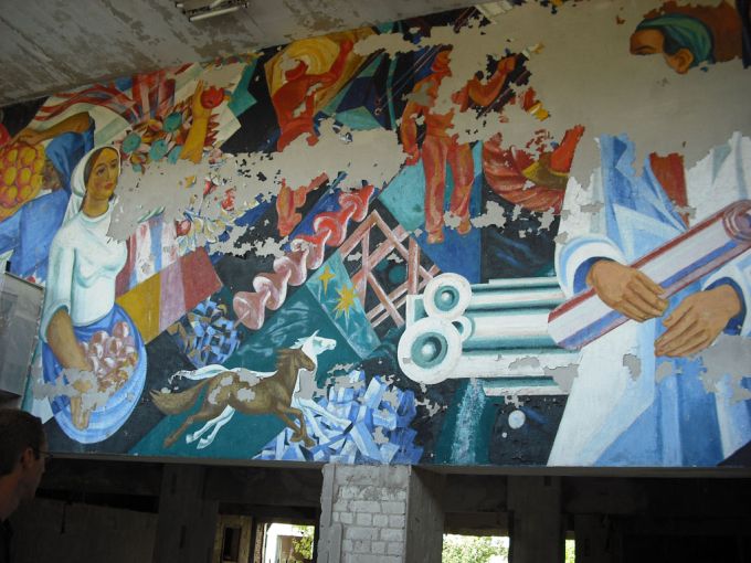 tenemos un mural donde podemos ver pintados mujeres caballos y un homb re con documentos en sus mano y varias cosas mas