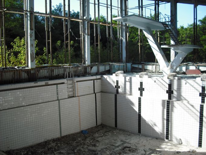 Vemos una piscina sin agua acabada la baldosas reventadas vemos escaleras y mucho mas de la estructura