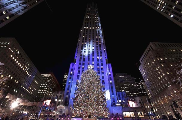 Vemos un conjunto de altos edificios iluminados y también un hermoso árbol de navidad iluminado se destaca entre todos los otros