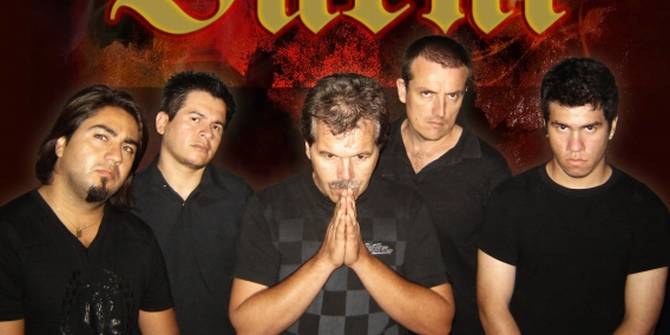 Un grupo cinco músicos todos con ropa negra y uno con las manos puestas en oración