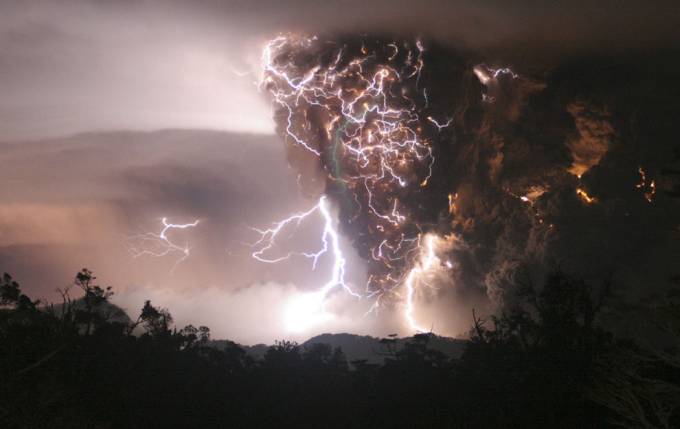 Vemos unos truenos que caen cerca al volcan a lo lejos tambien se ve una montaña
