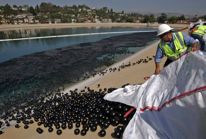 Vemos a unos hombres uniformados trabajando tiran al mar unas pelotas negras de plastico