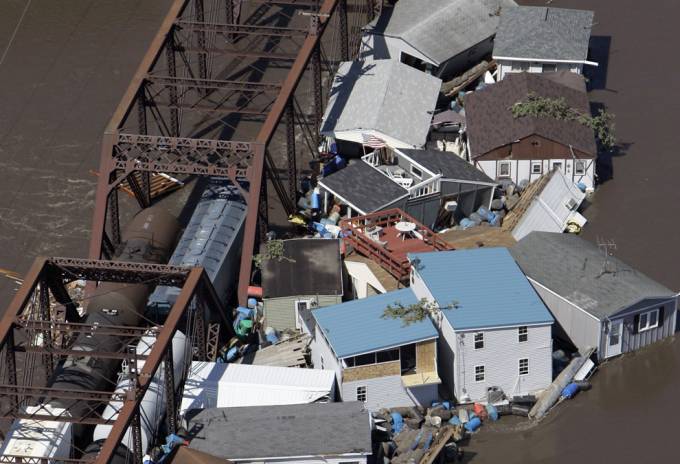Vemos unas casas destruidas y la carrilera del tren y un puente después de un desbordamiento de un rio