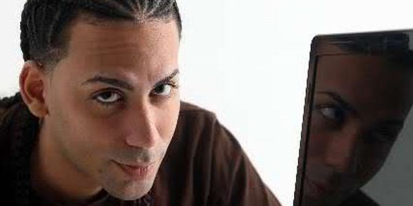 Un hombre joven con trenzas que mira muy sonriente a la camara