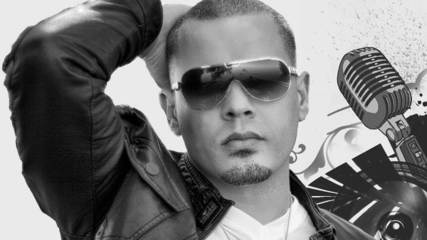 Un joven con gafas  y chaqueta negra de cuero que toca su cabeza cerca un micrófono