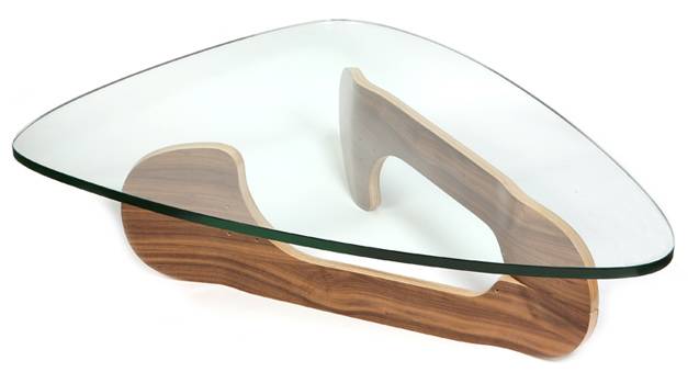 Vemos a una mesa de vidrio en una forma como de plancha y tiene como base cuatro patinetas