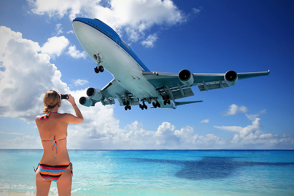 El avion ahora a poca altura se va y una turista con bikini de rayas le toma una foto