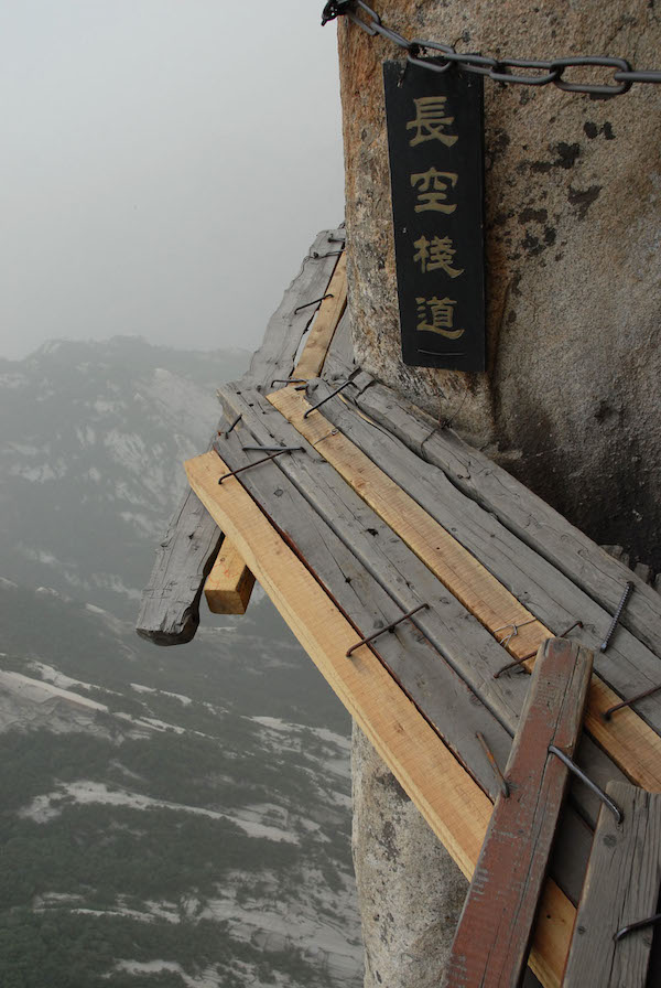 Vemos otra vez la montaña  con sus tablones y vemos un aviso de precaucion en caracteres chinos  