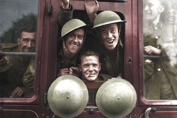 Vemos soldados sonrientes a través  del vidrio de un carro antiguo llevan cascos redondos en color verde militar
