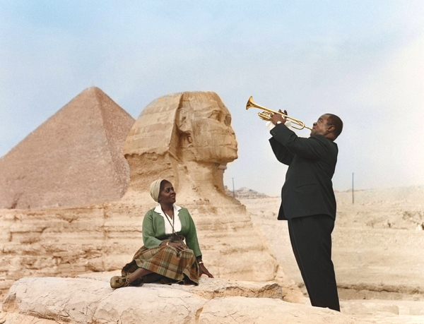 Una pareja afro en el desierto el toca la trompeta para ella al fondo la esfinge de giza